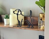 Beagle line art sculpture styled among candles and greenery on a shelf. Its minimalist single line design makes it a versatile home decor piece or thoughtful dog memorial gift.