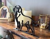 Angled side view of a minimalist Labrador or Golden Retriever sculpture, made from a single continuous black line and 3D printed in matte filament. Shows alert stance, floppy ears, and raised tail. Set on a wooden shelf with LED candles, gold candle holder, and other dog-themed art. A perfect shelf accent, pet memorial, or unique gift for dog owners and lovers.