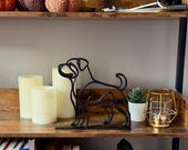 Minimalist black Rottweiler sculpture displayed as modern shelf decor with cozy fall accents.