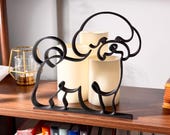 Sitting Bichon Frise line art sculpture with detailed cotton-ball fluffy coat displayed on a wooden shelf with warm glowing candles and a colorful bookshelf in the background — minimalist 3D printed Bichon Frise decor and a sweet Bichon Frise gift for dog moms, white fluffy dog lovers, and Bichon owners.