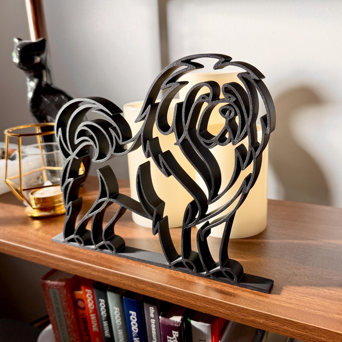 Close-up of Tibetan Mastiff line art decor with fluffy ears and a rounded muzzle, displayed on a shelf beside candles and greenery.