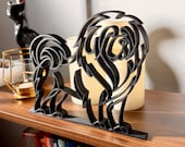 Close-up of Tibetan Mastiff line art decor with fluffy ears and a rounded muzzle, displayed on a shelf beside candles and greenery.