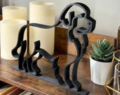 Newfoundland Dog silhouette sculpture crafted in minimalist line art style, matte black finish, shown on a rustic wood shelf with candles and a succulent. Unique handmade home decor for dog lovers and breed enthusiasts. 3D printed from premium PLA, this lightweight yet durable statue is an eye-catching accent for living rooms, desks, or libraries. Thoughtful gift idea for Newfoundland owners and pet parents.