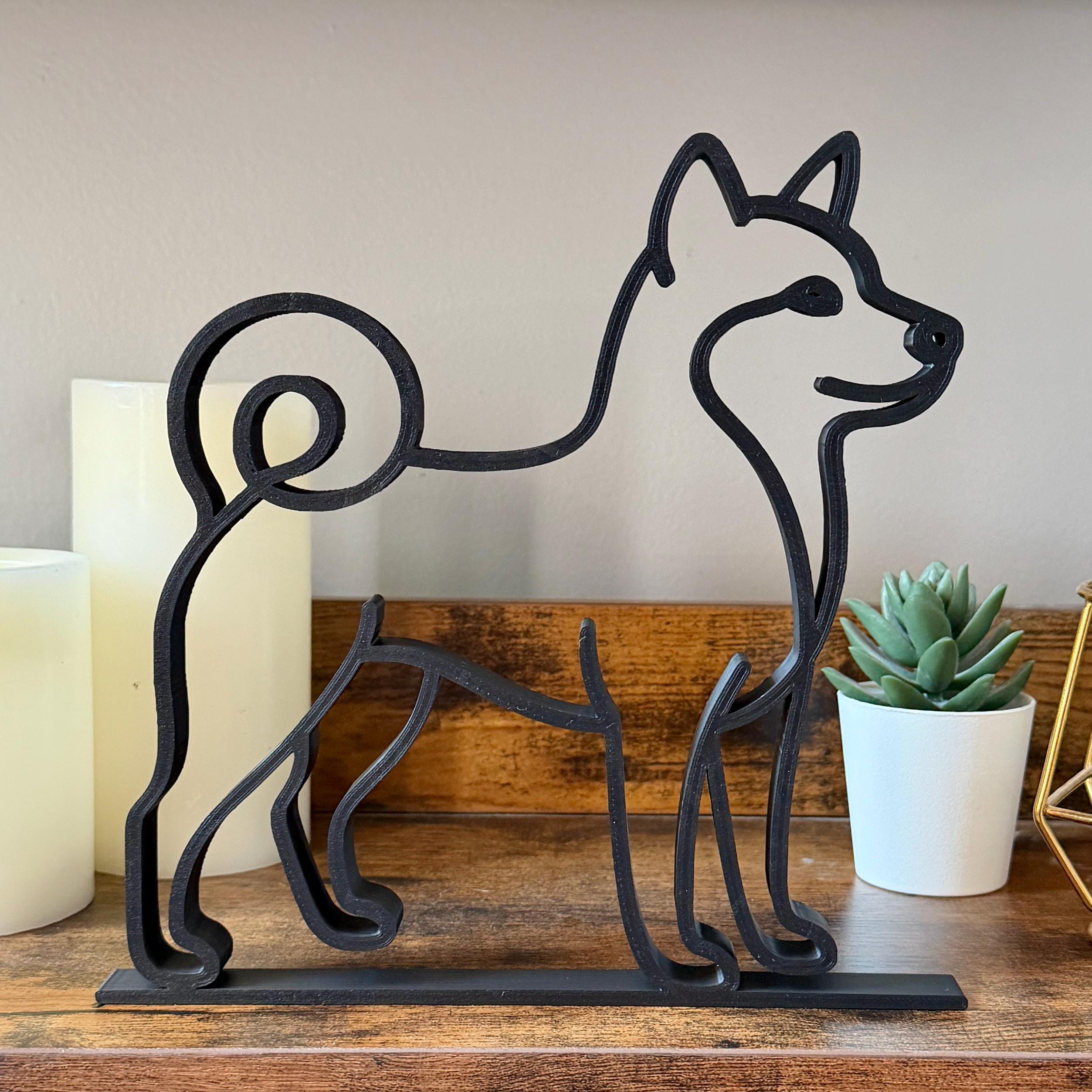Matte black dachshund line art sculpture on minimalist white shelf with books