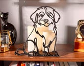 Sitting Bernedoodle line art sculpture with fluffy doodle coat displayed on a wooden shelf with warm glowing candles, a vintage clock, and a colorful bookshelf in the background — minimalist 3D printed Bernedoodle decor and a heartfelt Bernedoodle gift for dog moms, doodle owners, and Bernese poodle mix lovers.