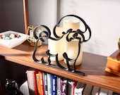 Close-up of a matte black Bichon Frise line art sculpture showing the breed's plush curly coat and cheerful expression, styled on a wooden shelf with vintage decor and bookshelf accents — 3D printed minimalist Bichon Frise decor and a thoughtful Bichon gift for dog moms and dog dads.