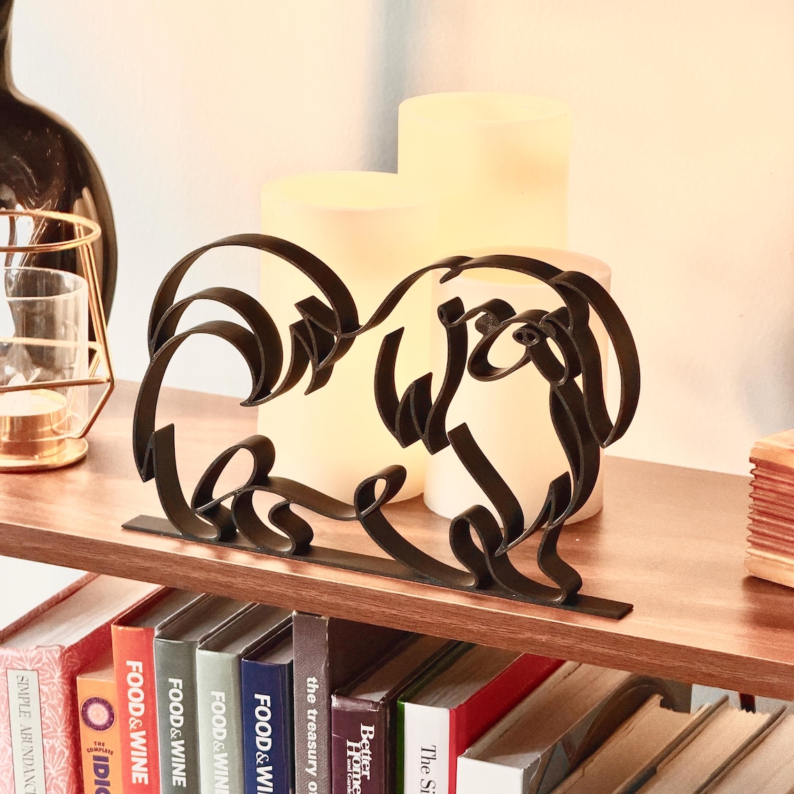 Pekingese dog line art statue in matte black on styled bookshelf with cookbooks and candles, thoughtful gift idea for Pekingese owners