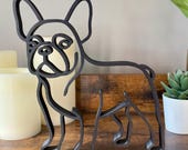 Front-facing French Bulldog sculpture in single-line art style. Matte black accent piece styled with candles and plants, perfect Frenchie gift or modern shelf decor.
