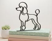 Minimalist black line art sculpture of a Poodle with iconic groomed silhouette, displayed standing upright on a stack of pastel books with a small succulent plant beside it. Modern pet decor perfect for bookshelves, office styling, or dog lover gifts.