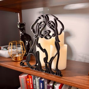 Close-up of a matte black Bernedoodle line art sculpture showing the breed's fluffy curly coat and gentle expression, styled with vintage candles, glass lantern, and cookbooks — 3D printed minimalist Bernedoodle decor and a unique Bernedoodle gift for doodle moms and dog lovers.