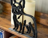 Side angle of a French Bulldog line art sculpture in matte black, standing with alert ears. Displayed on a shelf with candles, showing its sleek, modern silhouette.