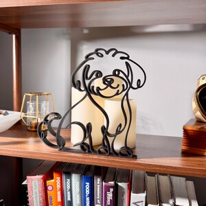 Sitting Maltipoo line art sculpture with detailed fluffy curly coat displayed on a wooden shelf with warm glowing candles and a colorful bookshelf in the background — minimalist 3D printed Maltipoo decor and a heartfelt Maltipoo gift for dog moms, doodle owners, and cute dog lovers.
