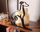 Side perspective of a black Italian Greyhound line art figurine displayed with decorative candles on a bookshelf, showing the sculpture’s depth and clean contemporary design.