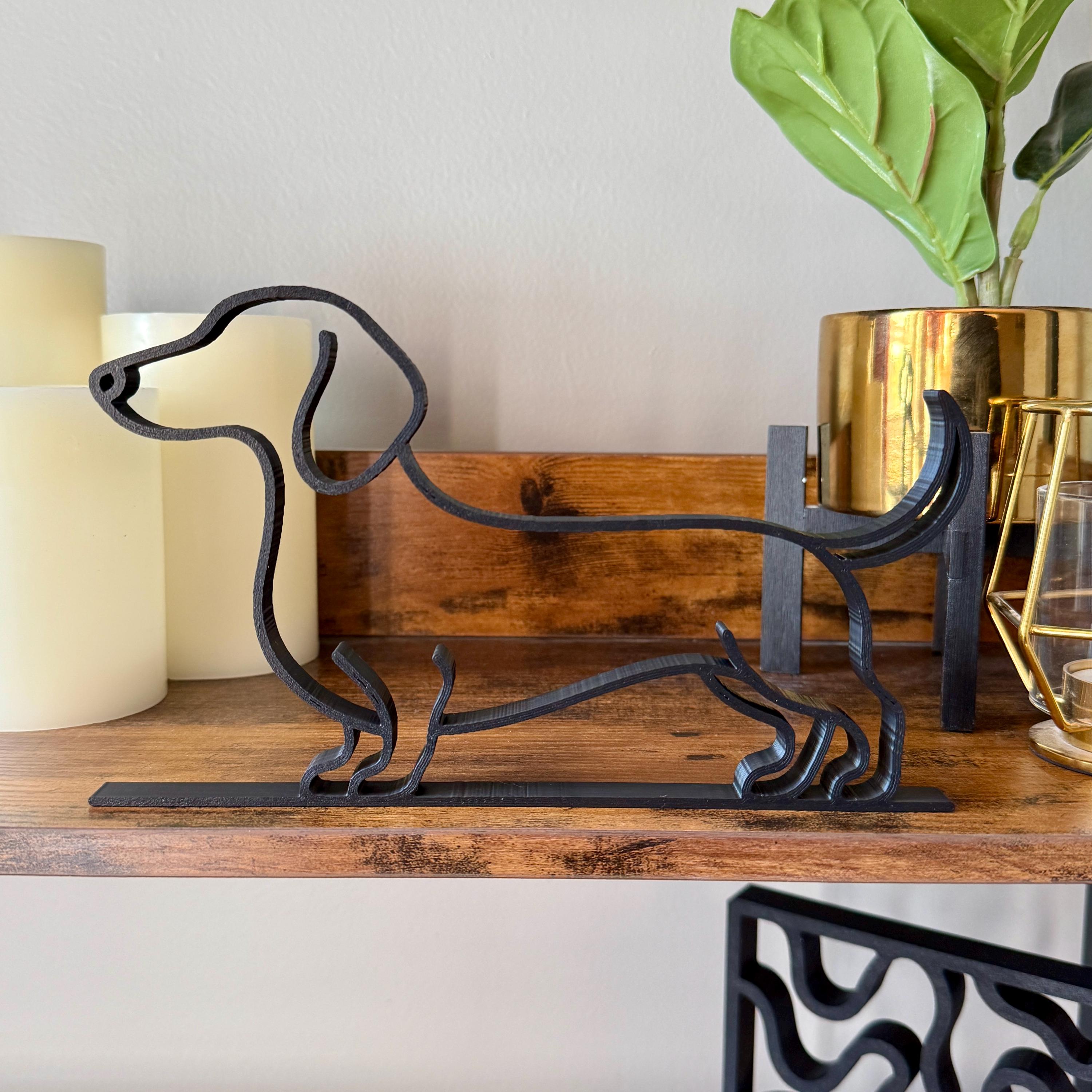 Matte black dachshund line art sculpture showing the breed's distinctive long body and short legs
