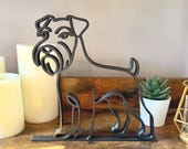 Minimalist Schnauzer line art sculpture in matte black displayed on a rustic wooden shelf with candles and succulent.