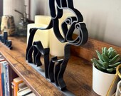 Black matte French Bulldog sculpture designed in a clean, continuous single line art style. Displayed on a modern wood shelf with candles, succulent, and decor, creating a chic accent for dog lovers. Minimalist Frenchie statue crafted from durable PLA, lightweight yet sturdy. Perfect decor piece for office, home shelves, or as a thoughtful gift for French Bulldog fans. Modern French Bulldog art blends seamlessly into any interior style.