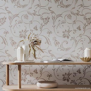 May include: A wall stencil featuring a repeating floral pattern in light brown on a white background. The design consists of swirling vines, leaves, and stylized blossoms. The text royaldesignstudio.com is printed in the bottom right corner.