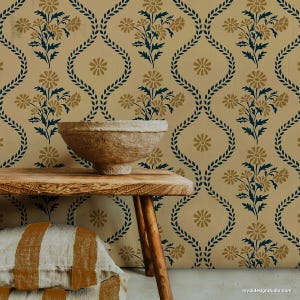 May include: A stencil featuring a repeating pattern of stylized floral sprigs and wreaths. The stencil is painted on a beige wall with a brown bowl and pillows in the foreground.