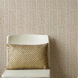 May include: A white chair with a gold mesh pillow in front of a beige wallpaper with a chevron pattern.