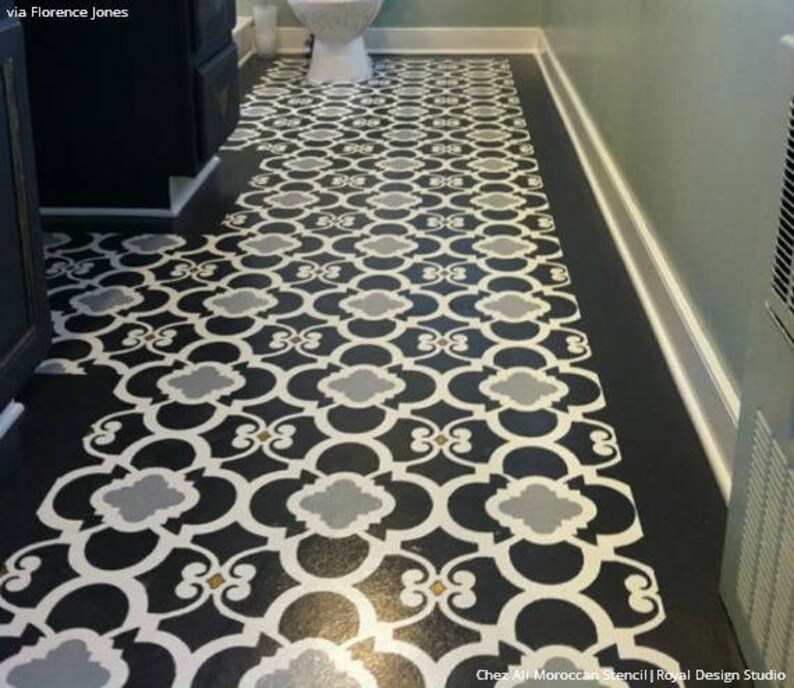 May include: A black and white patterned floor stencil with a Moroccan design. The stencil is laid out on a black floor and shows a repeating pattern of interlocking circles and squares.