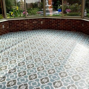 May include: A sunroom floor with a stencil design painted in gray, white, and blue. The design is a repeating pattern of interlocking shapes.