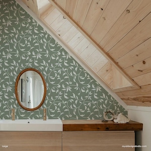 May include: A bathroom with a green and white leaf patterned wallpaper, a wooden vanity with a white sink, and a round mirror with a wooden frame.