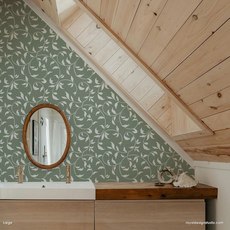 May include: A bathroom with a green and white leaf patterned wallpaper, a wooden vanity with a white sink, and a round mirror with a wooden frame.