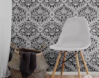 May include: A white chair with wooden legs sits in front of a wall with a black and white floral wallpaper pattern. A woven basket with a black and white pattern sits on the floor.