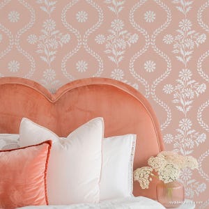 May include: A pink and white floral patterned wallpaper with a peach-colored headboard and white pillows on a bed. The headboard is shaped like a heart.