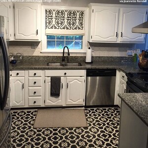 May include: A kitchen with white cabinets and a black and white patterned floor. The floor is a stencil design. The kitchen has a stainless steel dishwasher and a black and white patterned window valance.