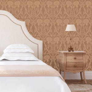 May include: A bedroom interior with a white headboard bed, white bedding, a wooden nightstand with a lamp, and a brown patterned wallpaper with a floral design.