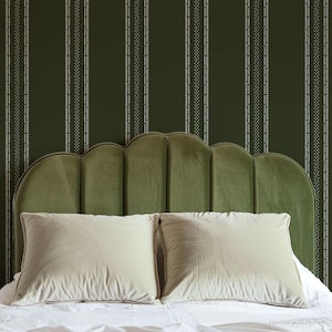 May include: A green velvet headboard with a scalloped design, featuring two white pillows on a white bed with a green and white striped wallpaper background.