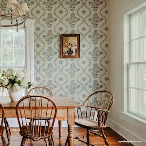 May include: A dining room with a wooden table and chairs. The walls are decorated with a floral wallpaper stencil pattern. A framed painting hangs on the wall.