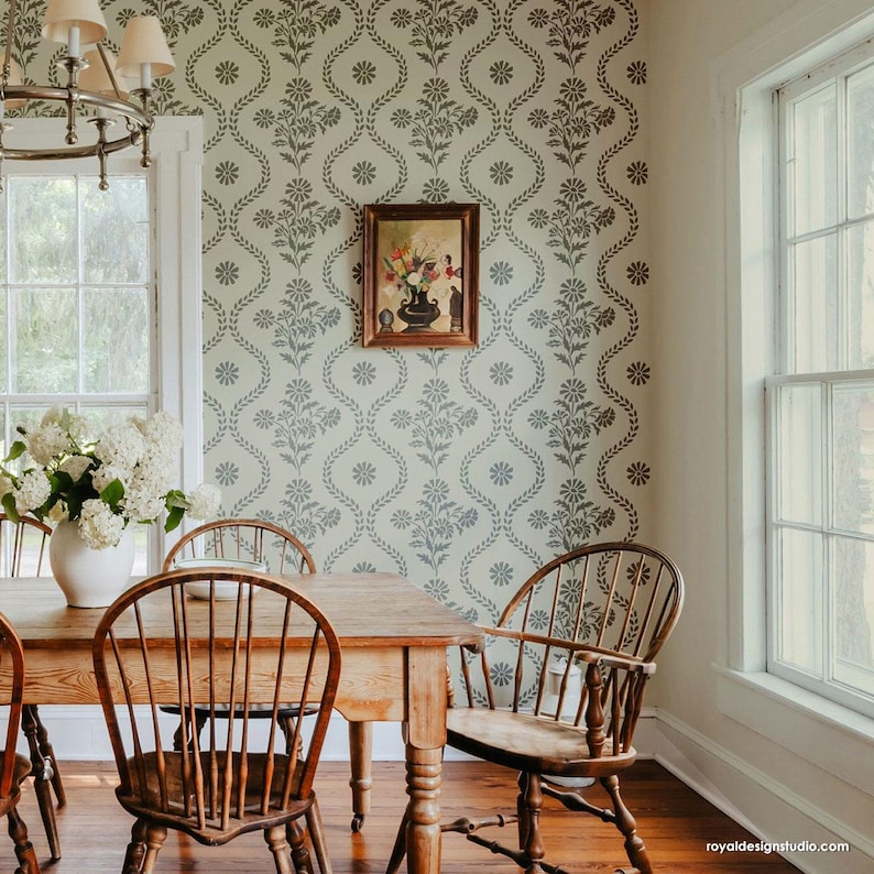May include: A dining room with a wooden table and chairs. The walls are decorated with a floral wallpaper stencil pattern. A framed painting hangs on the wall.