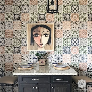 May include: A kitchen island with a black countertop and cabinets. The backsplash is a patterned stencil design in shades of green, brown, and gray. A painting of a woman's face hangs on the wall above the countertop. There are two wine glasses and a plant on the countertop.