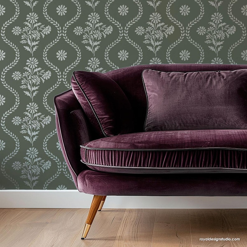 May include: A purple velvet sofa with a floral patterned wallpaper behind it. The sofa has a tufted back and a gold metal base.