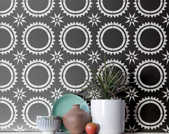 Peut inclure: Un motif de pochoir géométrique noir et blanc avec un motif répétitif de cercle et d'étoile. Le pochoir est sur un mur gris avec une plante dans un pot blanc et quelques bols décoratifs sur un comptoir blanc.