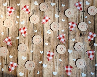 May include: Overhead shot of a wooden surface scattered with pie-shaped and heart-shaped cutouts. The pie cutouts are beige with a starburst design, and the gingham-patterned cutouts are red and white. White heart-shaped cutouts are also scattered across the surface.