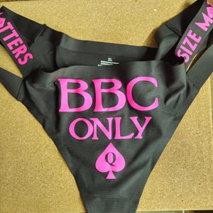 Peut inclure: Sous-vêtements noirs avec l'inscription "BBC ONLY" en rose vif, ainsi qu'un symbole de pique rose. Les bretelles portent les inscriptions "SIZE MATTERS" et "POTTERS" en rose. Taille XL.