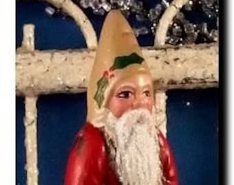 May include: A vintage-style Santa Claus figurine with a red coat, white beard, and a green and white hat. He is holding a sack and a stick in his hands.