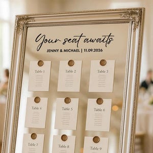 Puede incluir: Un plano de asientos enmarcado con el texto "Your seat awaits" sobre los nombres "JENNY & MICHAEL" y la fecha "11.09.2026". Nueve tarjetas están fijadas, cada una con un número de mesa y sellada con un sello de cera dorado.