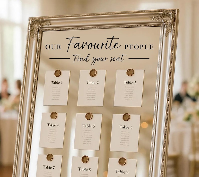 May include: A silver framed seating chart with the text "OUR Favourite PEOPLE Find your seat". Nine cards are affixed to the chart, each labeled with a table number and sealed with a gold wax seal.