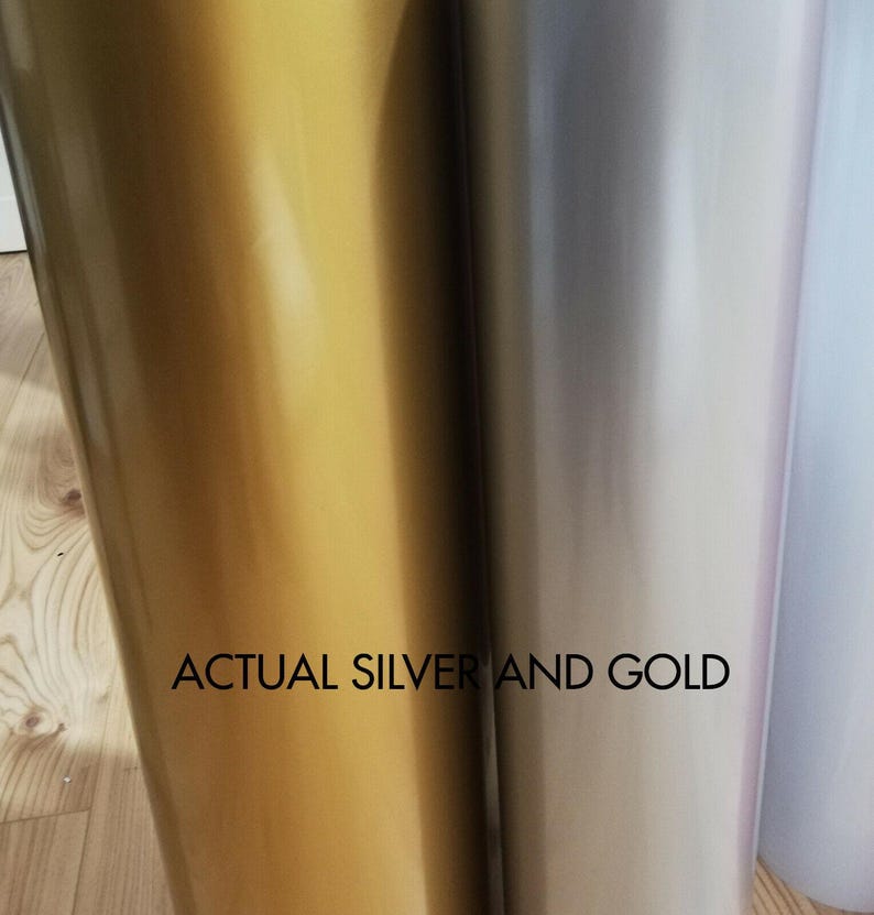 May include: Close-up of two rolls of shiny vinyl material, one gold and one silver. The text "ACTUAL SILVER AND GOLD" is printed in black across the bottom of the image. The vinyl has a smooth, reflective surface.