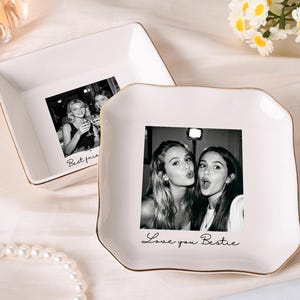 May include: Two white ceramic trinket dishes with gold-toned rims. Each dish features a black and white photograph printed in the center. The front dish displays a photo of two people with the text "Love you Bestie" printed below the image.