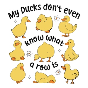 Può includere: Grafica bianca con otto paperi gialli dei cartoni animati in varie pose. Il testo "My Ducks don't even know what a row is" è scritto in un carattere giocoso sopra e intorno alle anatre. Sono inclusi anche piccoli fiori e stelle.