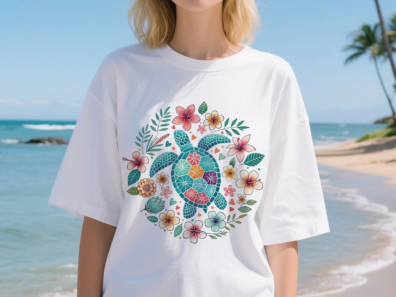 May include: White t-shirt featuring a colorful sea turtle design surrounded by flowers and leaves. The turtle has a mosaic-like pattern on its shell, with a variety of colors. The flowers are in shades of pink, orange, and yellow.