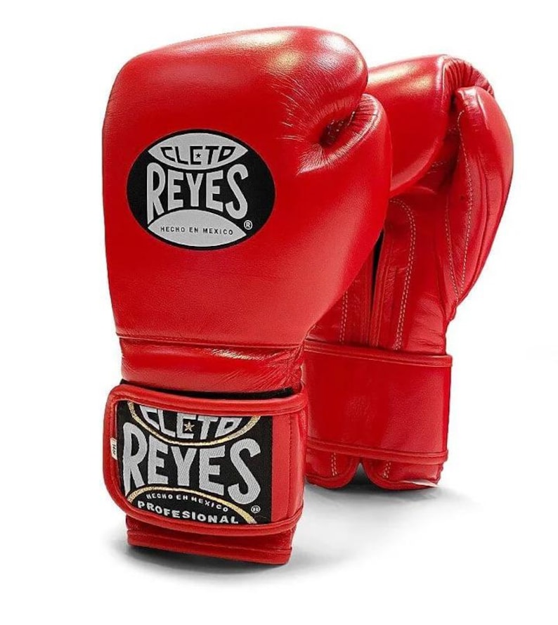 Red Cleto Reyes professional boxing gloves featuring a hook-and-loop closure, white inner thumb, and iconic branding, showcased in a dynamic 3D view on a white background.