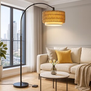 Puede incluir: Una lámpara de pie arqueada moderna con una pantalla de ratán tejido y una estructura de metal negro. La lámpara está cerca de una ventana y un sofá crema, creando un ambiente cálido. La altura de la lámpara es de aproximadamente 183 cm.