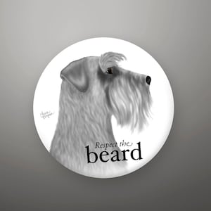 May include: A white button with a black and white illustration of a Schnauzer dog with the text "Respect the beard" printed on it.