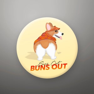 May include: A round button with a cartoon image of a corgi wearing a red and orange scarf. The text "Suns Out Buns Out" is written in red and orange on the button.